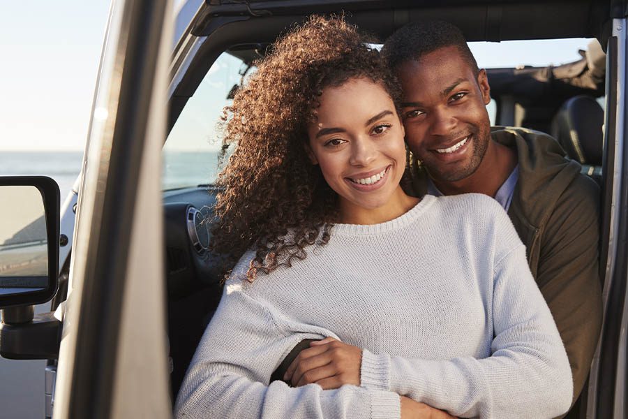 Personal Insurance - Young Couple Embracing by the Car Before Going for a Drive