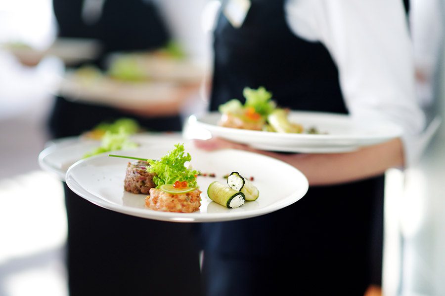 Specialized Business Insurance - Closeup of a Waiter Carrying Dinner Plates in a High End Restaurant